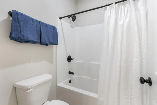 a bath room with a toilet and a shower curtain