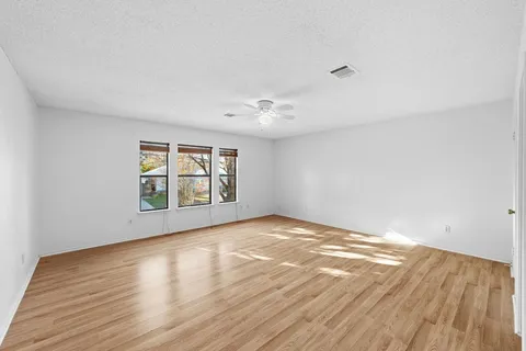 a view of an empty room with a window and wooden floor