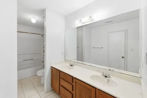 a bathroom with a double vanity sink mirror and toilet