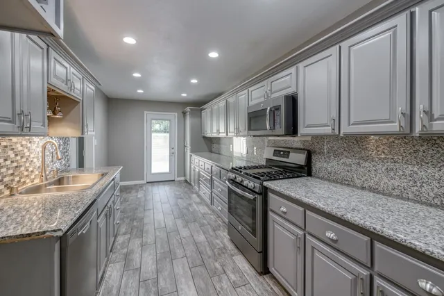 a kitchen with stainless steel appliances granite countertop wooden cabinets a stove top oven a sink and dishwasher