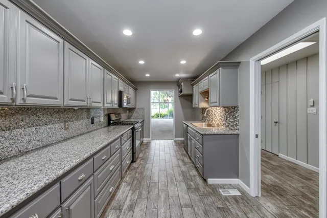 a kitchen with granite countertop a sink wooden floor and stainless steel appliances