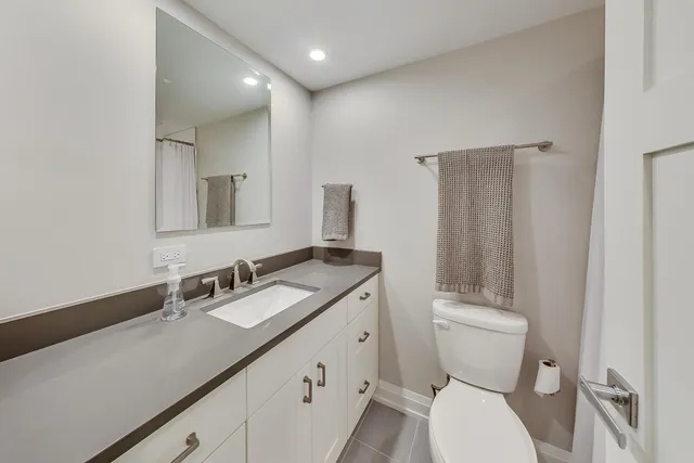 a bathroom with a granite countertop sink toilet and mirror