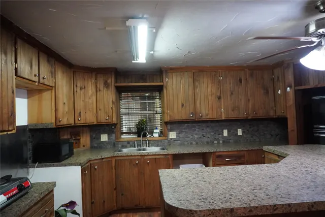 a kitchen with granite countertop wooden cabinets a sink and a stove