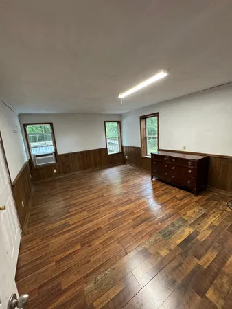 a view of an empty room with a window and wooden floor