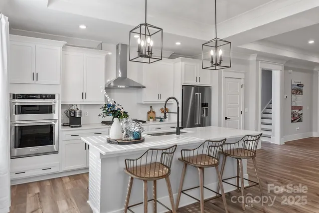 a kitchen with stainless steel appliances a dining table chairs and stove
