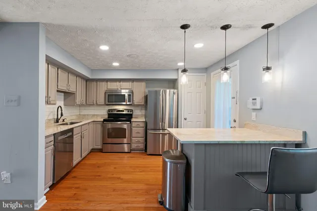 a kitchen with a sink stainless steel appliances and wooden floor