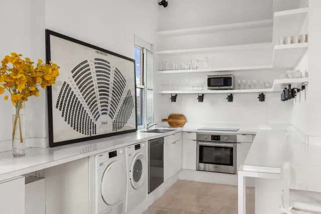 a kitchen with a sink a stove and white cabinets with wooden floor