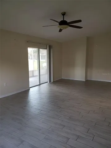 a view of an empty room with a window and wooden floor