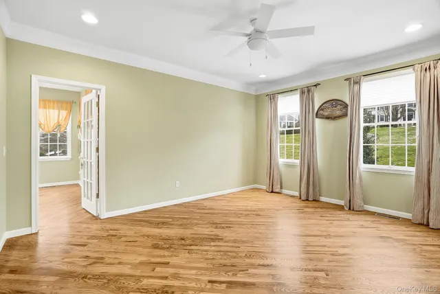 a view of an empty room with window and wooden floor