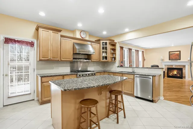 a kitchen with stainless steel appliances granite countertop a stove top oven a sink dishwasher a dining table and chairs with wooden floor