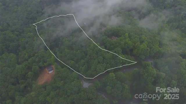 an aerial view of residential house with outdoor space and trees all around