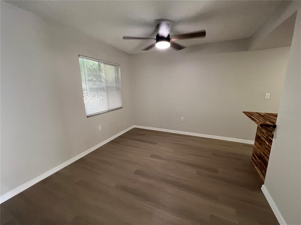 2611 Pine Lake Terrace, Unit B Sarasota, FL 34237 - Photo 9 of 21 an empty room with wooden floor fan and windows