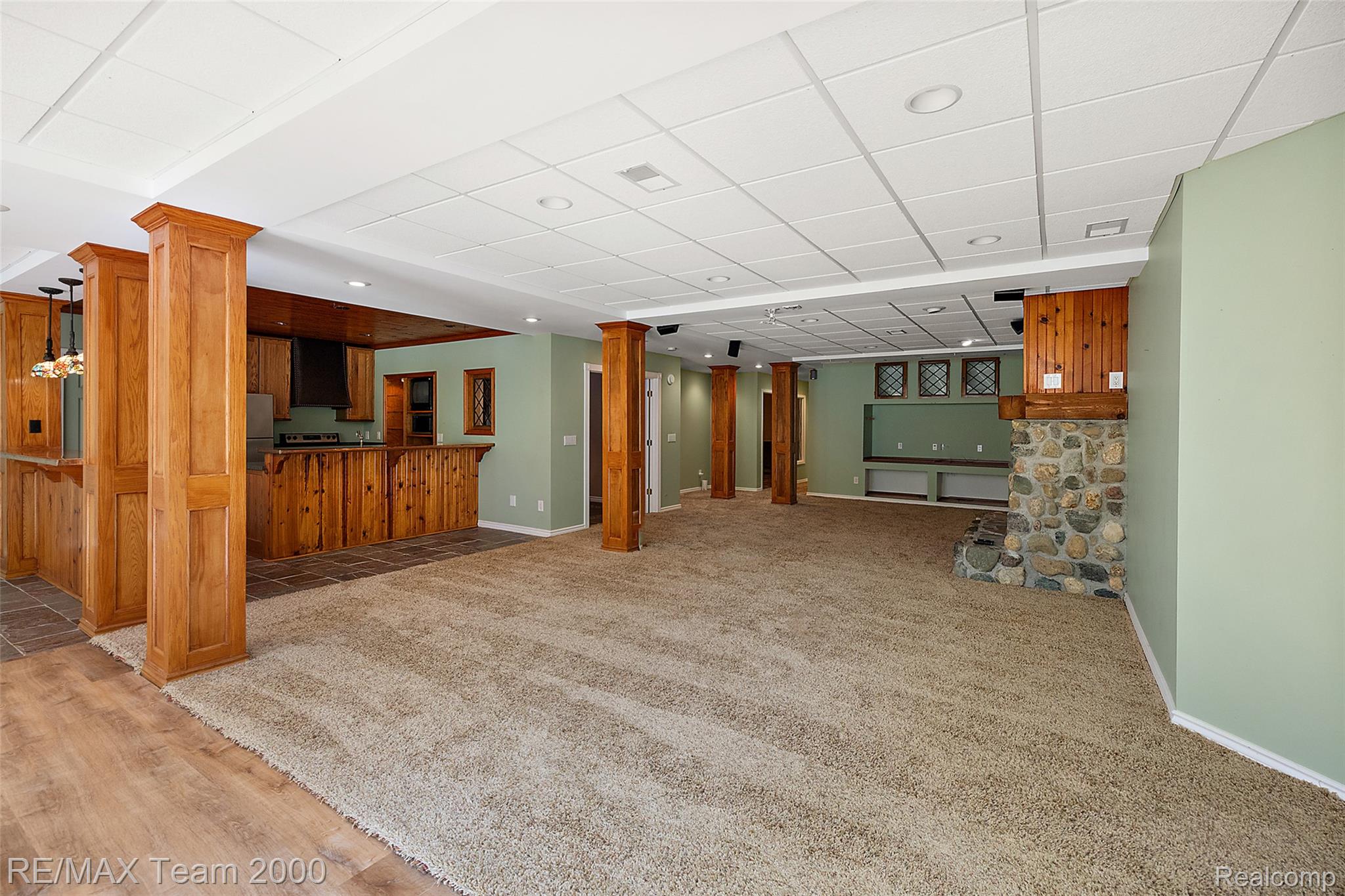 630 Sheldon Court Rochester, MI 48306 - Photo 78 of 94 Unfurnished living room featuring a paneled ceiling, ornate columns, bar, light carpet, and light wood-type flooring