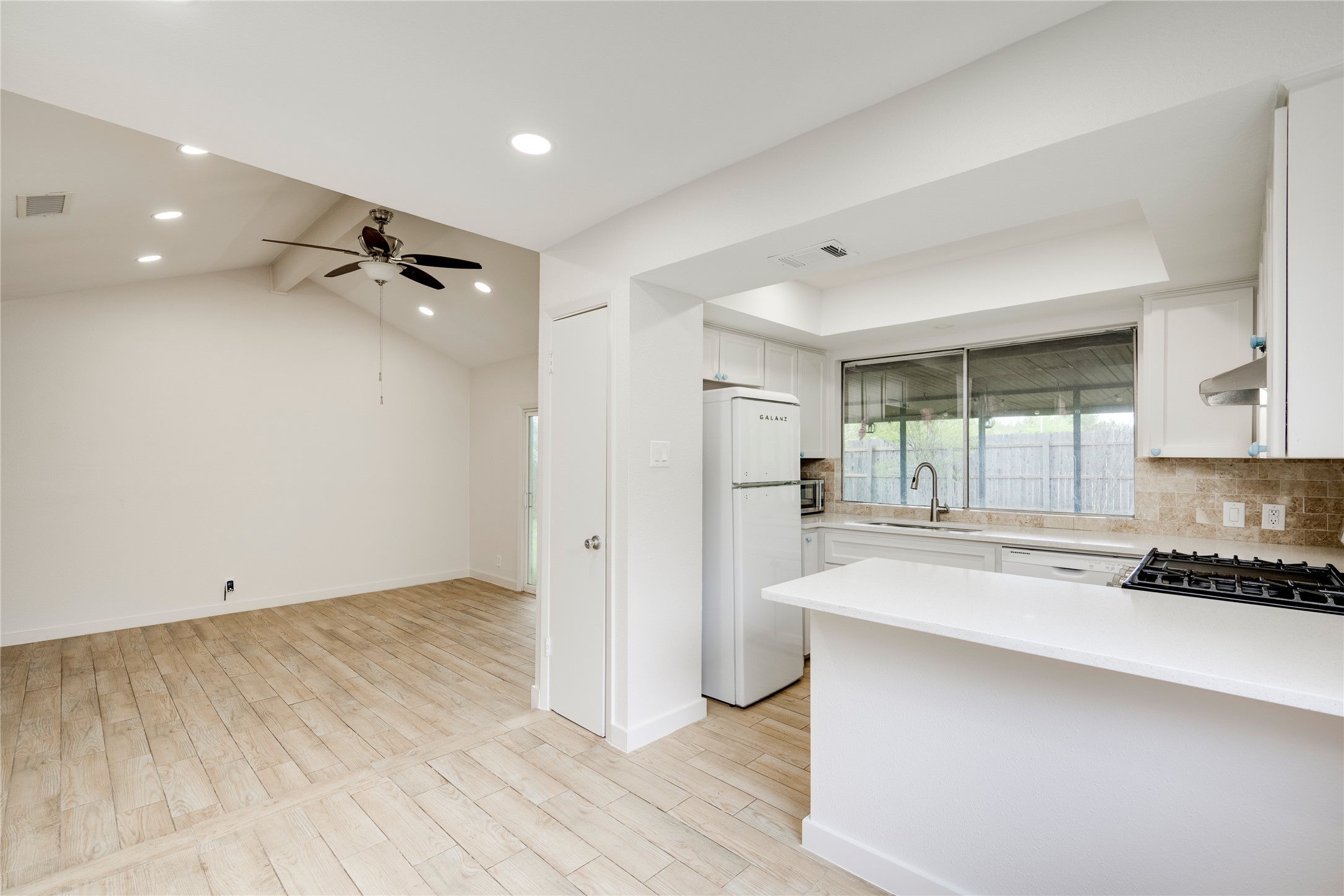 4811 Brushy Ridge Drive Austin, TX 78744 - Photo 21 of 39 Kitchen featuring white cabinets, light wood finished floors, freestanding refrigerator, beamed ceiling, and recessed lighting
