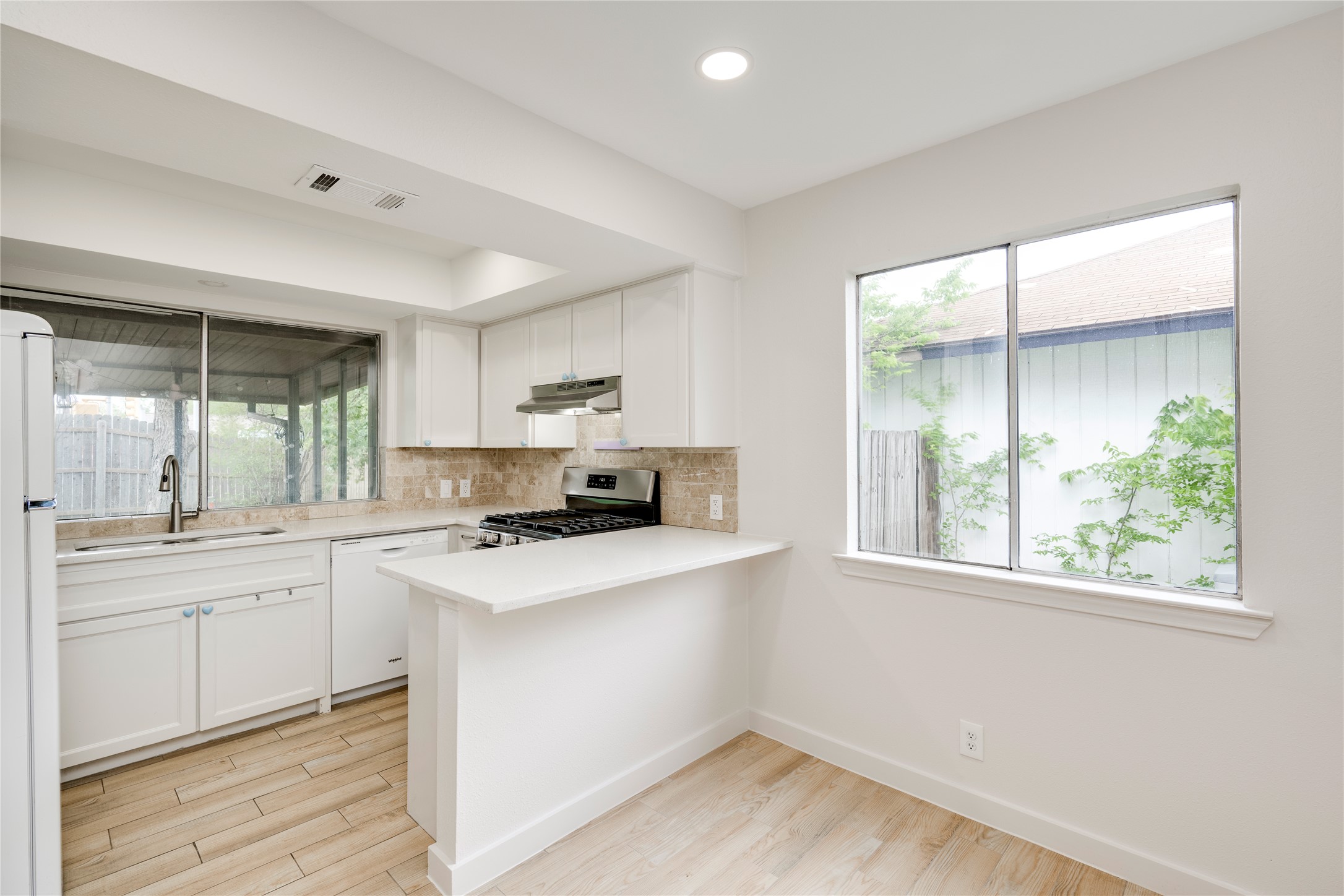 4811 Brushy Ridge Drive Austin, TX 78744 - Photo 22 of 39 Kitchen featuring white cabinets, tasteful backsplash, light wood-style floors, white appliances, and recessed lighting