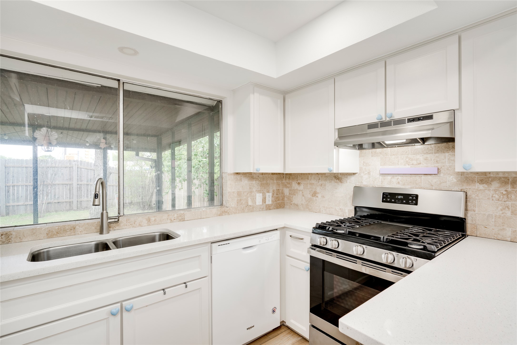 4811 Brushy Ridge Drive Austin, TX 78744 - Photo 25 of 39 Kitchen featuring stainless steel gas range oven, dishwasher, white cabinetry, light stone countertops, and tasteful backsplash