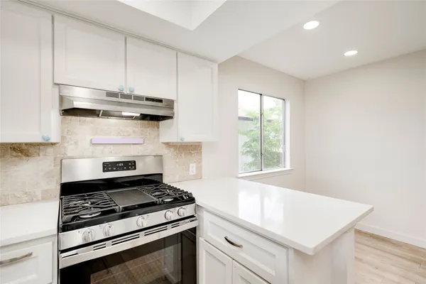 a kitchen with a stove and a white wooden cabinets