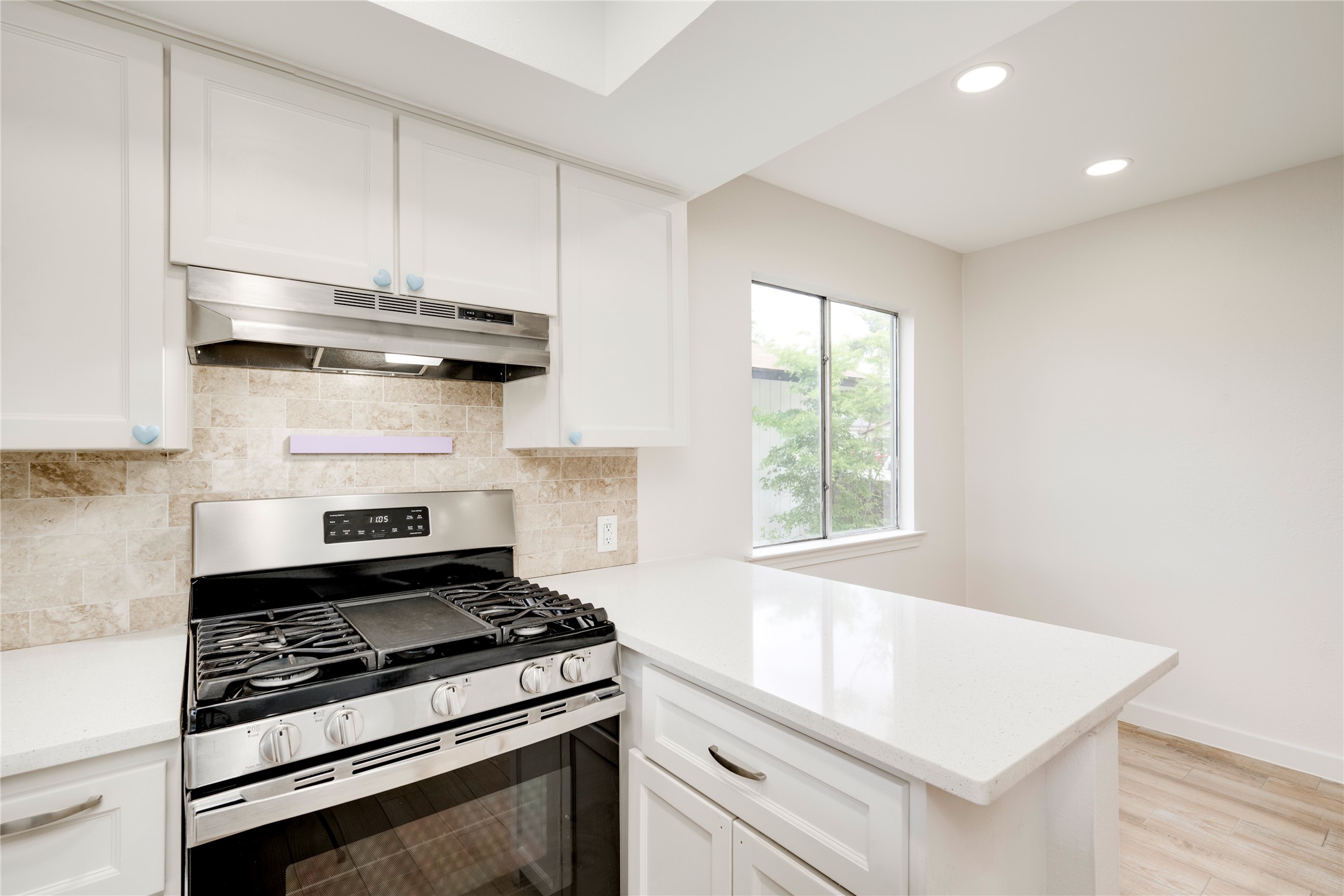 4811 Brushy Ridge Drive Austin, TX 78744 - Photo 26 of 39 Kitchen featuring stainless steel gas range oven, recessed lighting, a peninsula, white cabinetry, and backsplash