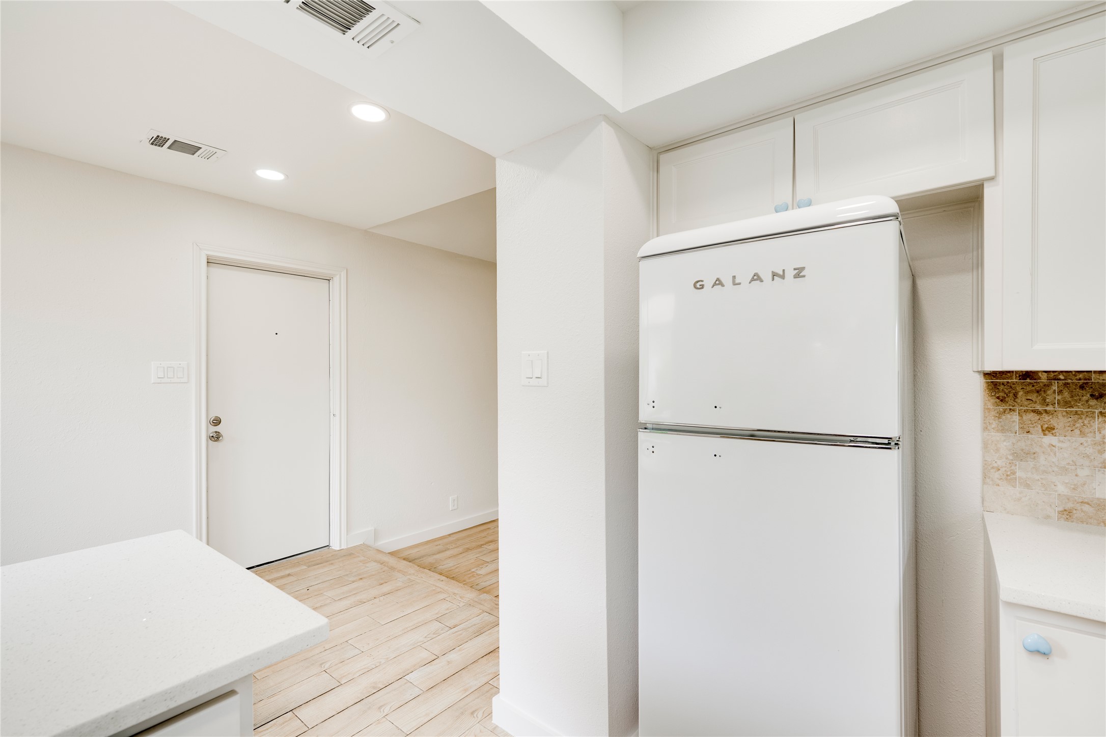 4811 Brushy Ridge Drive Austin, TX 78744 - Photo 27 of 39 Kitchen featuring freestanding refrigerator, white cabinets, recessed lighting, light wood-style flooring, and light stone counters