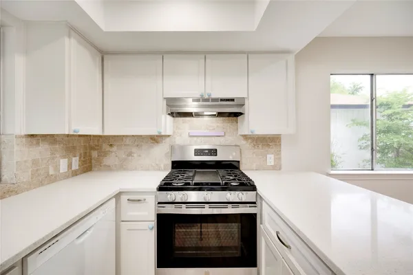 a kitchen with granite countertop a stove sink and cabinets