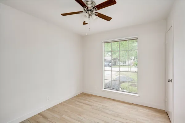 an empty room with a window and a ceiling fan