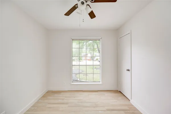 a view of empty room with wooden floor and fan
