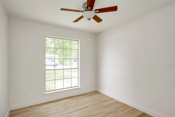 an empty room with windows and fan