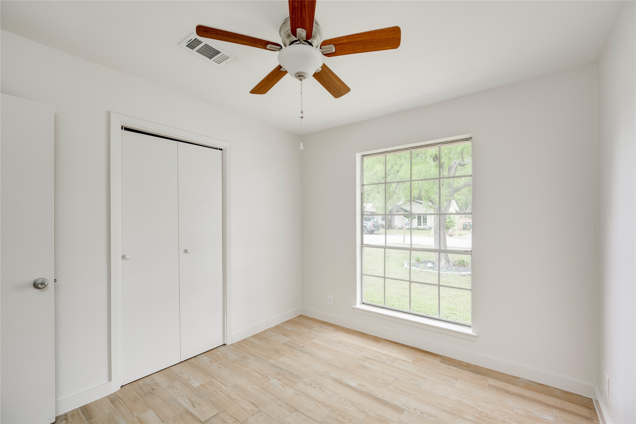 4811 Brushy Ridge Drive Austin, TX 78744 - Photo 33 of 39 Unfurnished bedroom with light wood-type flooring, a closet, and a ceiling fan