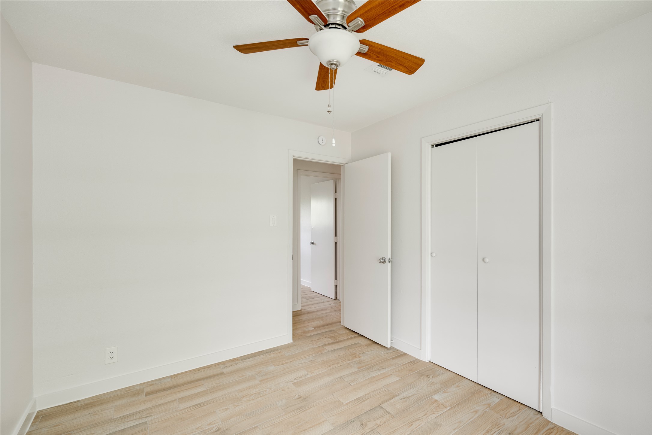 4811 Brushy Ridge Drive Austin, TX 78744 - Photo 34 of 39 Unfurnished bedroom featuring light wood finished floors, a ceiling fan, and a closet