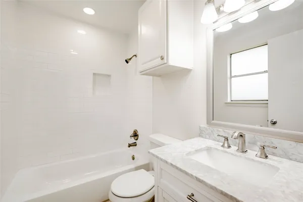 a bathroom with a granite countertop sink a toilet and bathtub