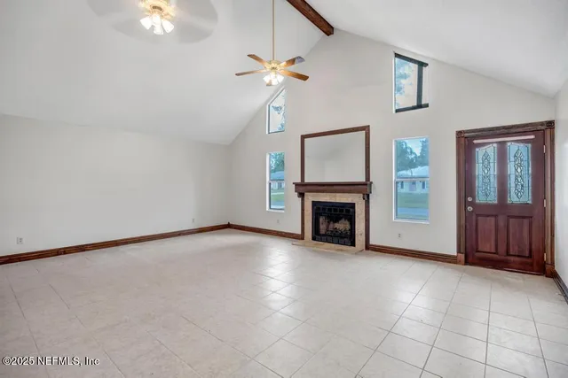 a view of an empty room with chandelier fan and fire place