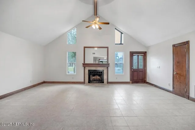 an empty room with windows fireplace and a chandelier