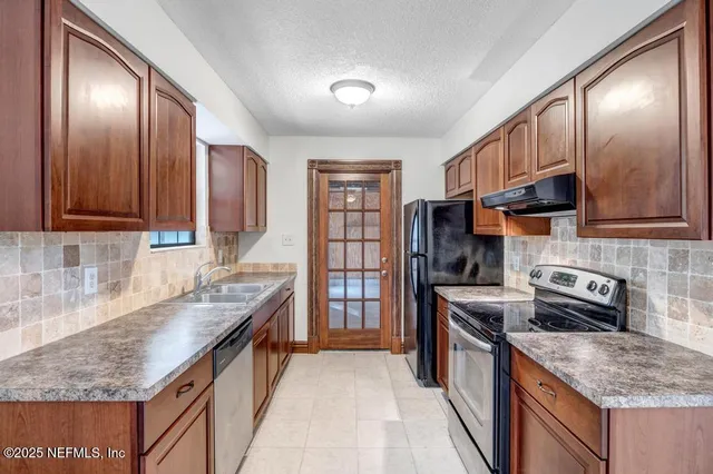 a kitchen with stainless steel appliances granite countertop a stove a sink dishwasher oven a refrigerator with wooden cabinets and floor