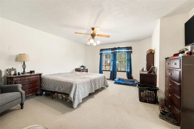 a spacious bedroom with a bed a couch and a chandelier