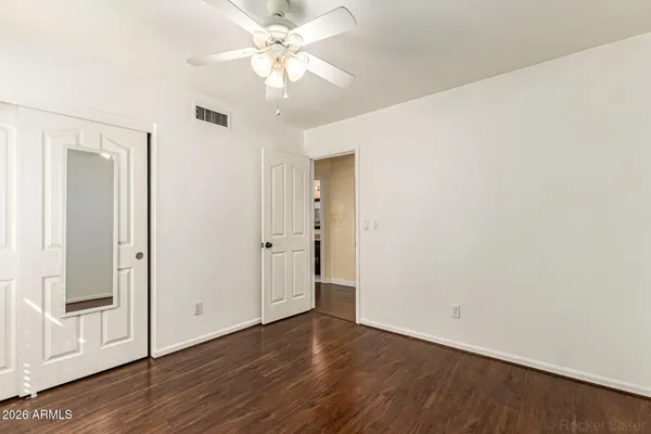 an empty room with wooden floor and fan