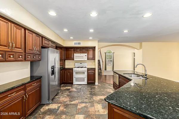 a kitchen with stainless steel appliances granite countertop a sink stove and refrigerator