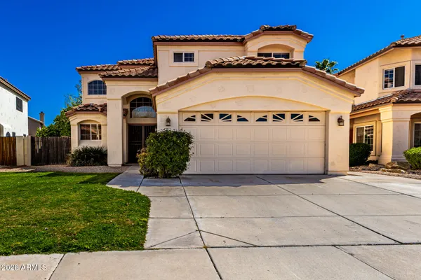 a view of a white house with a small yard and large parking space