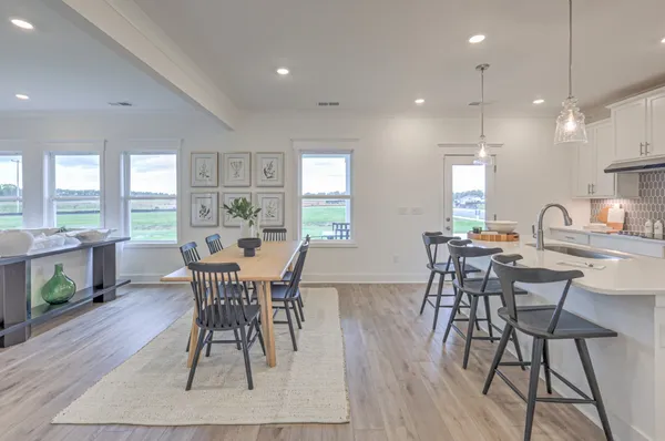 a kitchen with stainless steel appliances kitchen island granite countertop a dining table chairs refrigerator and sink