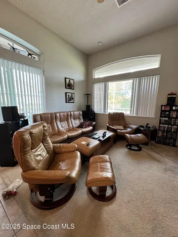 a living room with furniture a large window and a chandelier