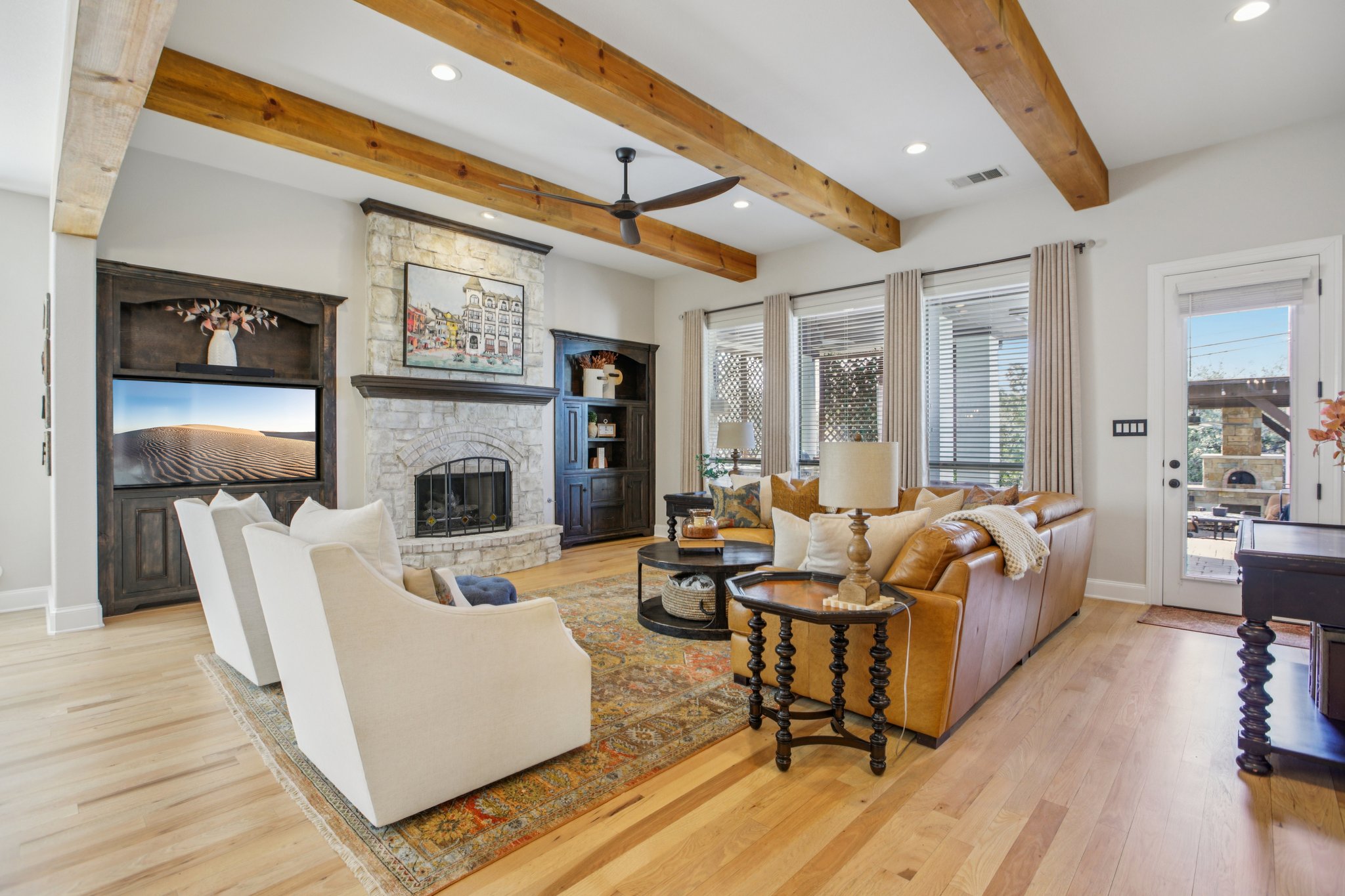 436 SANTALUZ Path Austin, TX 78732 - Photo 9 of 34 Beautiful, gleaming hardwood floors span the main living areas, adding warmth and elegance. Striking wood-beamed ceilings frame the expansive, open living areas. The living room is anchored by a stunning floor-to-ceiling stone fireplace.Walls of windows flood the living space with natural light and offer views of the backyard oasis. Glass doors dissolve the barrier between the indoors and the outdoor living areas, perfect for entertaining.