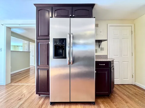 a kitchen with a refrigerator and wooden floor