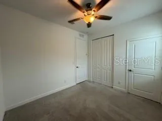 an empty room with closet and a ceiling fan