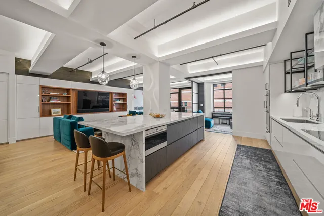 a large white kitchen with a wooden floor and stainless steel appliances
