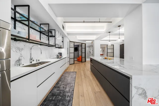 a large white kitchen with stainless steel appliances granite countertop lots of counter top space and wooden floor