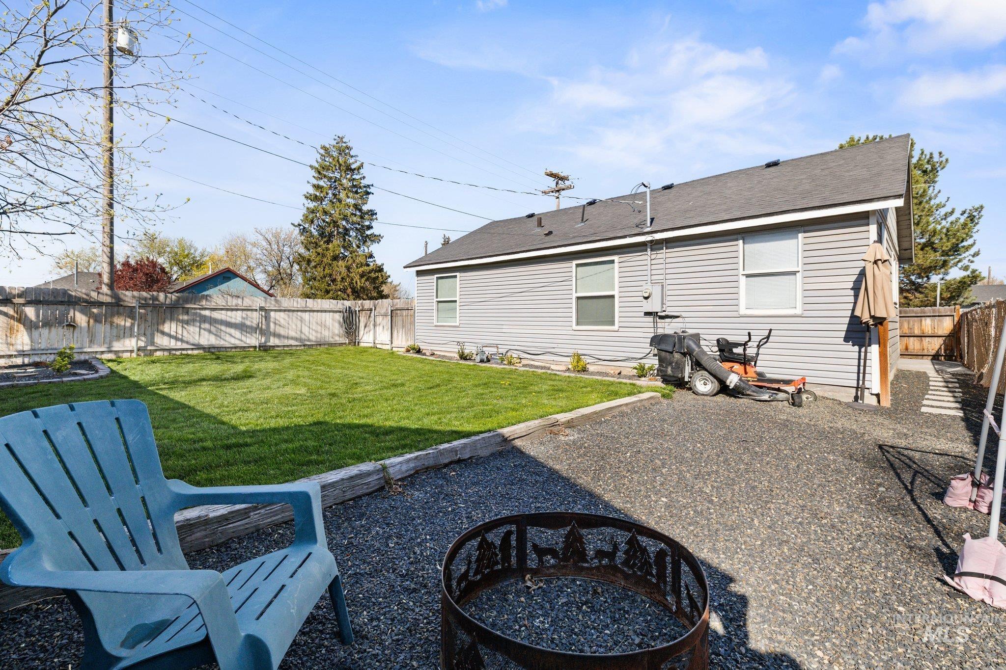 1504 2nd Street North Nampa, ID 83687 - Photo 24 of 29 Back of property featuring a patio area, a fenced backyard, an outdoor fire pit, and a shingled roof