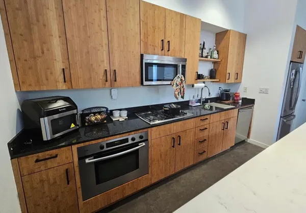 a kitchen with stainless steel appliances a stove a microwave a sink and cabinets