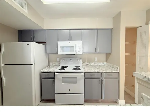 a white refrigerator freezer sitting inside of a kitchen with stainless steel appliances granite countertop cabinets and a refrigerator