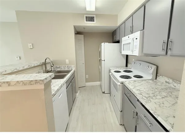 a kitchen that has a sink a stove and a refrigerator