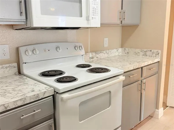 a kitchen with granite countertop white cabinets and white appliances