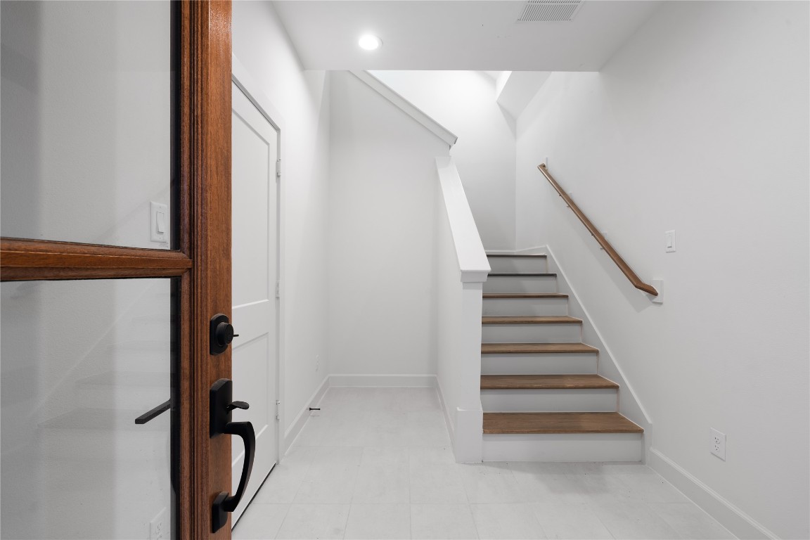 4710 Moving Meadows Houston, TX 77018 - Photo 6 of 42 The front entry opens to a clean, minimalist foyer with light tile flooring, a wood-accented staircase, and access to the first-floor bedroom suite. The space establishes the home’s neutral palette and modern finishes.